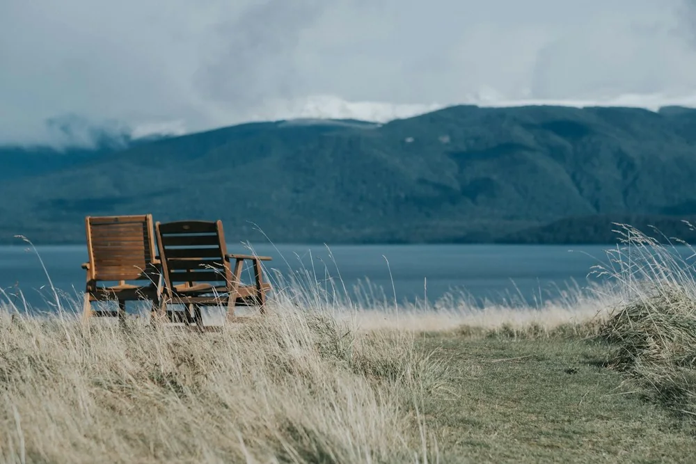 Two wooden chairs looking out across calm water